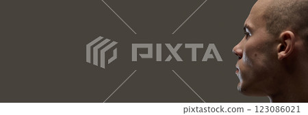 Banner. Intense male profile with sharp features and strong jawline looking into distance against dark background. 123086021