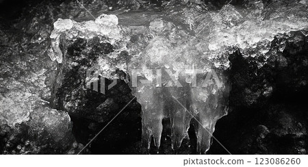 Close-up of ice formations on rugged rocks in a monochrome winter landscape. 123086260