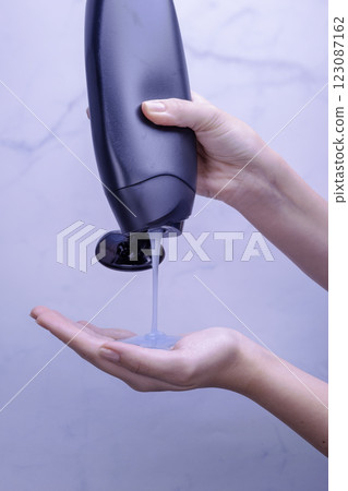 Shower gel in white bottle poured into woman palm Shower gel in white bottle poured into woman palm 123087162