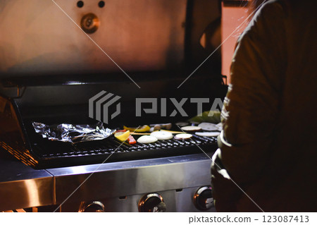 晚上，一名婦女在露營地的烤肉架上烤蔬菜 123087413