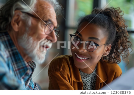 A joyful conversation between a young woman and an elderly man in a cozy cafe setting. 123088376