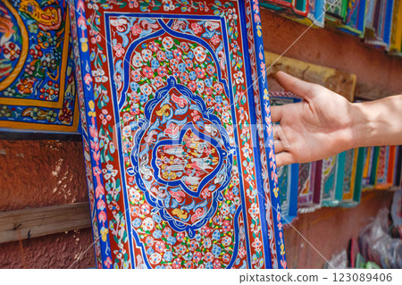 Hand showing Colorful wooden trays and plates displayed in craft shop, Marrakech Hand showing Colorful wooden trays and plates displayed in craft shop, Marrakech 123089406