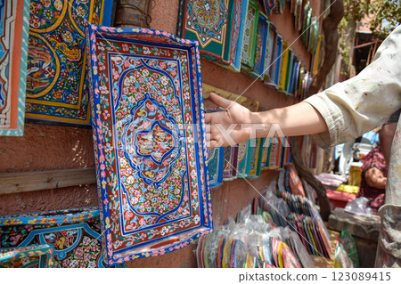 Hand showing Colorful wooden trays and plates displayed in craft shop, Marrakech 123089415