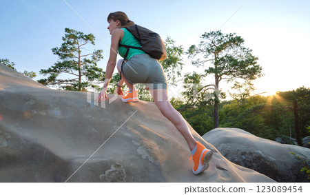 Young woman climbing alone on rocky mountain path. Female hiker enjoying difficult challenge on wilderness trail. Active way of life concept Young woman climbing alone on rocky mountain path. Female hiker enjoying difficult challenge on wilderness trail. Active way of life concept 123089454