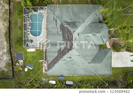 Wind damaged house roof with missing asphalt shingles after hurricane Ian in Florida. Repair of home rooftop concept Wind damaged house roof with missing asphalt shingles after hurricane Ian in Florida. Repair of home rooftop concept 123089482
