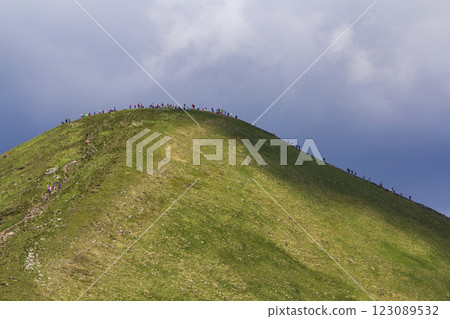 View from afar of lit by summer sun mountain Hoverla with lots of people traveling up and down by tourist route under bright blue sky. Beauty of nature, danger to ecology, tourism and hiking concept. 123089532