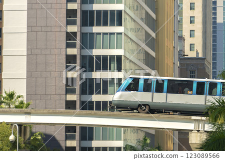 Urban transportation in downtown district of Miami Brickell in Florida USA. Metrorail city train car on high railroad over street traffic between skyscraper buildings in modern American megapolis Urban transportation in downtown district of Miami Brickell in Florida USA. Metrorail city train car on high railroad over street traffic between skyscraper buildings in modern American megapolis 123089566