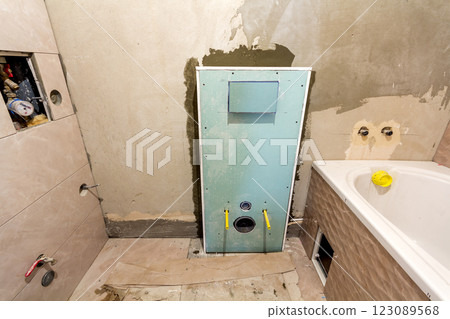 Unfinished reconstruction of bathroom or toilet with ceramic tiles installed on walls of drywall, place for lavatory and bath. 123089568