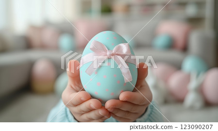 Child's hands hold a pastel Easter egg in a bright living room filled with festive decorations 123090207