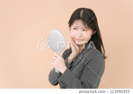 A woman in a suit looking in the mirror 123092955