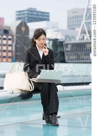 年輕女商人在戶外使用筆記型電腦時擔心 123093180