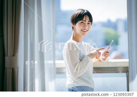A woman who operates a smartphone in the room 123093307
