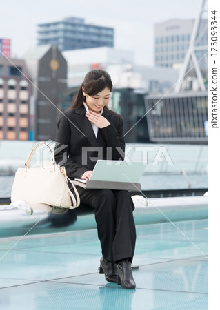 名古屋榮市 OASIS21 水上太空船,一位微笑的女商人正在戶外看著筆記型電腦 名古屋榮市 OASIS21 水上太空船,一位微笑的女商人正在戶外看著筆記型電腦 123093344