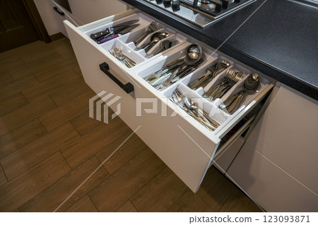 Stainless steel spoons, forks and knifes in cutlery box drawer in white kitchen cupboard Stainless steel spoons, forks and knifes in cutlery box drawer in white kitchen cupboard 123093871