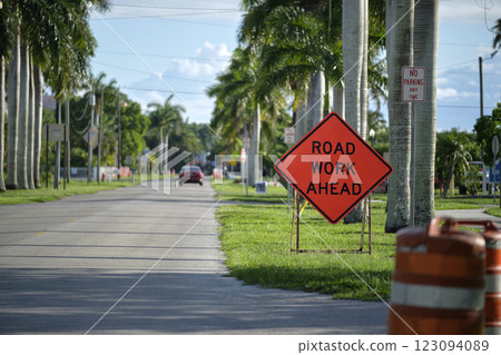 Road work ahead sign and barrier cones on street site as warning to cars about construction and utility works 123094089
