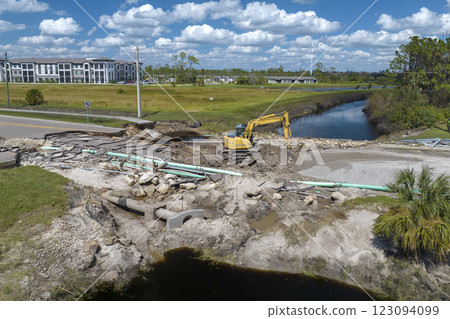 Road construction. Excavator repairing destroyed bridge after hurricane flooding water washed away asphalt in Florida. Construction equipment at roadwork site Road construction. Excavator repairing destroyed bridge after hurricane flooding water washed away asphalt in Florida. Construction equipment at roadwork site 123094099
