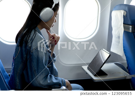 Young woman wearing headphones looking at tablet or computer Young woman wearing headphones looking at tablet or computer 123095655