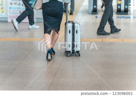 The feet of a business woman on a business trip or return from a trip with a suitcase at the station 123096001
