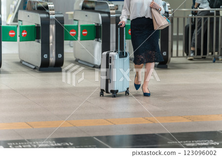 The feet of a business woman on a business trip or return from a trip with a suitcase at the station 123096002