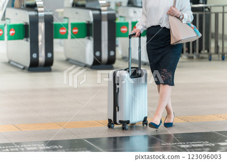 The feet of a business woman on a business trip or return from a trip with a suitcase at the station 123096003