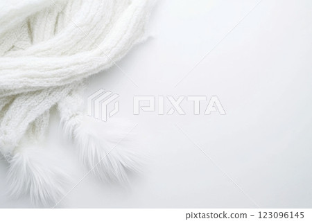 Soft white scarf with fluffy ends resting on a light surface Soft white scarf with fluffy ends resting on a light surface 123096145