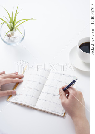 A woman's hand writing in a schedule book 123096709
