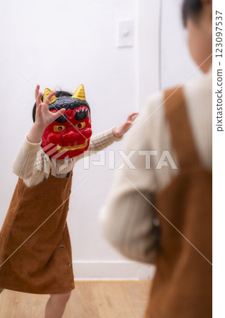 Two sisters wearing demon masks having fun throwing beans on Setsubun Two sisters wearing demon masks having fun throwing beans on Setsubun 123097537