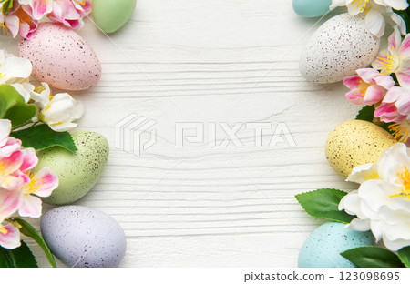 Colorful easter eggs and spring flowers creating a frame on white wood 123098695