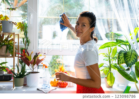 Woman manually washes the window of house with rag cleaner and mop inside the interior with home plants on windowsill and pumpkin decor. Restoring order and cleanliness in autumn, cleaning servise Woman manually washes the window of house with rag cleaner and mop inside the interior with home plants on windowsill and pumpkin decor. Restoring order and cleanliness in autumn, cleaning servise 123098786