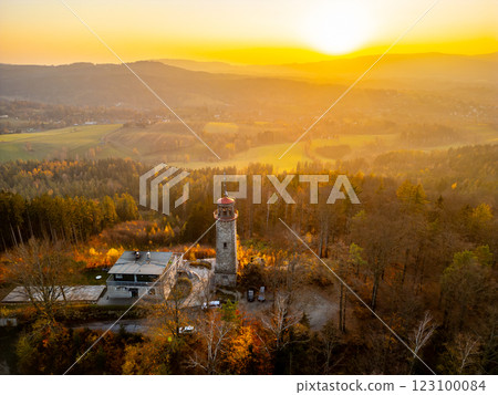 A golden autumn sunset casts warm light over the lookout tower on Prosec Ridge, surrounded by vibrant foliage and rolling hills near Jablonec nad Nisou in Czechia. A golden autumn sunset casts warm light over the lookout tower on Prosec Ridge, surrounded by vibrant foliage and rolling hills near Jablonec nad Nisou in Czechia. 123100084