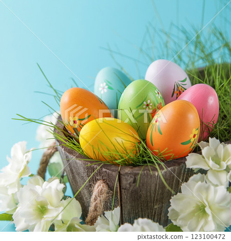 Happy Easter. Colorful Easter eggs and white flower on blue background. Square image Happy Easter. Colorful Easter eggs and white flower on blue background. Square image 123100472