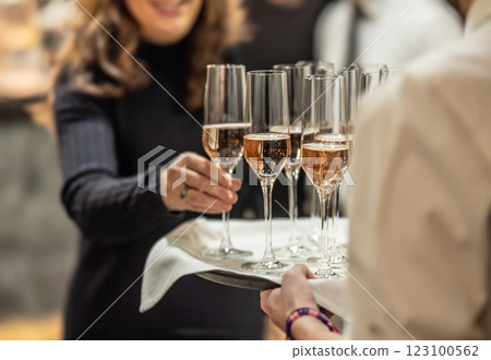 Young waiter holding a tray with champagne or prosecco at a wedding or gala event and offering guests a welcome drink 123100562