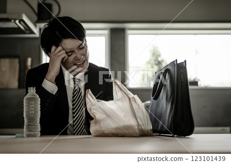 Asian businessman in a suit opening a convenience store bento in the dining room after returning home 123101439