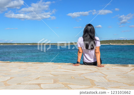Rear view of a relaxed tourist sitting on a retaining wall while looking at the sea against the sky, Rear view of a relaxed tourist sitting on a retaining wall while looking at the sea against the sky, 123101662