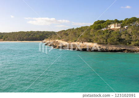 Coastal landscape with a point jutting into turquoise waters under clear skies, cala mondrago, mallorca, balearic island, spain 123102091