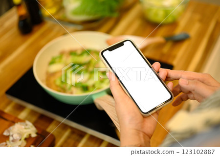 Close up woman checking her phone for recipe instructions while preparing a meal Close up woman checking her phone for recipe instructions while preparing a meal 123102887