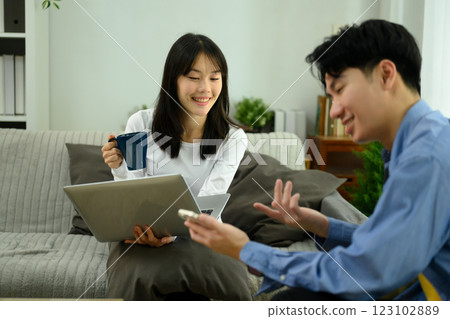 Happy young couple relaxing on a couch using laptop and smartphone 123102889