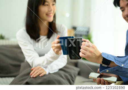 Happy young couple clinking coffee cups in a cozy living room 123102890