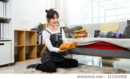 Beautiful woman folding clothes in a cozy living room Beautiful woman folding clothes in a cozy living room 123102898