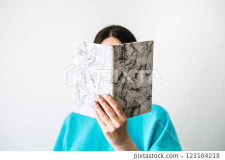 Smiling woman holding notebooks in minimalistic setting. Self-reflection through writing, creative expression, and personal growth with modern diary practices. 123104218
