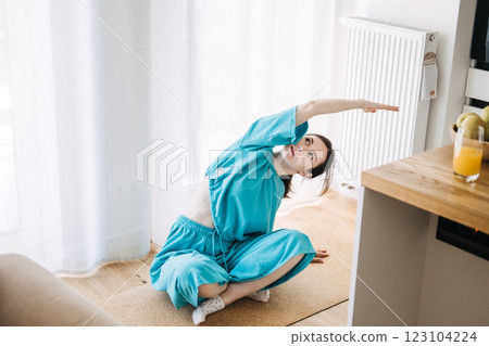 Woman practicing yoga pose in a bright modern home setting. At-home workouts, fitness in small spaces, remote exercise culture. 123104224