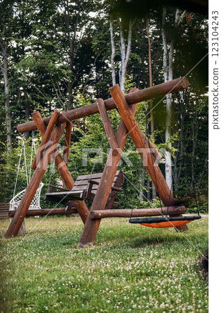 Wooden backyard swing set with natural surroundings, emphasizing relaxation, outdoor activities, and eco-friendly design in a rustic environment 123104243