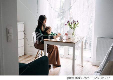 Mother working from home with toddler on lap. Remote work, parenting challenges, work-life balance, family time, flexible work arrangements Mother working from home with toddler on lap. Remote work, parenting challenges, work-life balance, family time, flexible work arrangements 123104246