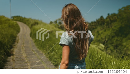 Long hair brunette girl walk green field meadow trail in Ubud, Bali island. Campuhan Ridge Walk scenery path picturesque hills. Outdoor lifestyle travel summer holiday vacation. Back view, 123104404