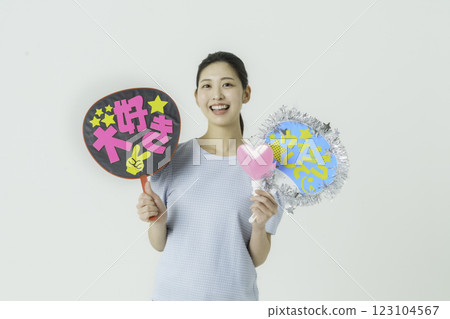 Oshikatsu: A young woman cheering on her idol with a fan on a white background Oshikatsu: A young woman cheering on her idol with a fan on a white background 123104567