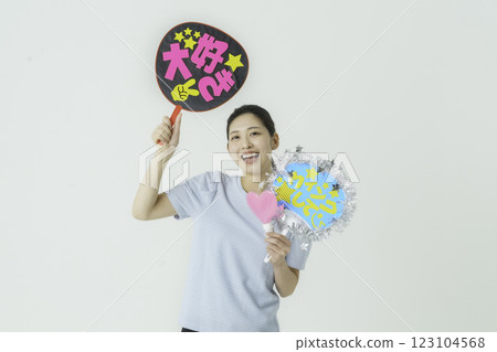 Oshikatsu: A young woman cheering on her idol with a fan on a white background Oshikatsu: A young woman cheering on her idol with a fan on a white background 123104568