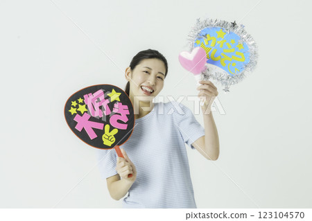 Oshikatsu: A young woman cheering on her idol with a fan on a white background 123104570