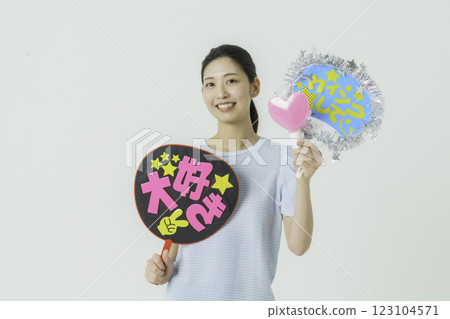Oshikatsu: A young woman cheering on her idol with a fan on a white background 123104571