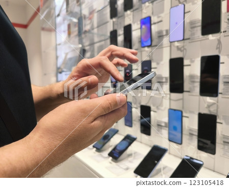 Closeup smart customer makes choice between smartphones in mobile phone store. Various selection in store of modern gadgets. 123105418