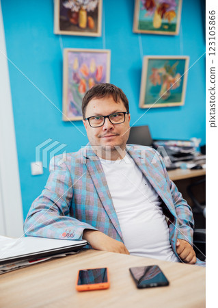Portrait of a young businessman working in the office at a laptop and holding a book. 123105866